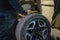 A car mechanic changes a tire on a wheel