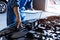 Car mechanic holding clipboard and checking to maintenance vehicle by customer claim order in auto repair shop garage. Engine