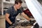 Car mechanic looking inside of engine in garage. Car motor repair. Problems and solutions