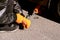 Car mechanic man wearing gloves lifts small orange car jack