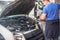 Car mechanic washes the car engine with pressurized water