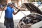 Car mechanic washes the car engine with pressurized water