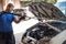 Car mechanic washes the car engine with pressurized water