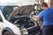 Car mechanic washes the car engine with pressurized water