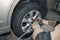 Car mechanic worker doing tire or wheel replacement with pneumatic wrench in garage of repair service station