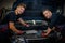 Car mechanics checking under hood in a workshop