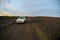 Car in the middle of a dirt field on a flattened road near the sundown of dusk