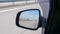 Car mirror. The car is driving on a high-speed highway in a desert area.