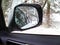 Car mirror. Forest in rear view mirror closeup. Reflected in a rearview. In the background forest. Winter