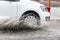 Car motion through big puddle of water splashes from the wheels on the street road. Water splash rain texture