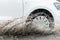 Car motion through big puddle of water splashes from the wheels on the street road. Water splash rain texture