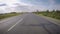 The car moves along the road along the field on a summer day