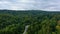 Car moves on a winding road among forest and mountains. Aerial drone view, zoom in