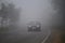 Car moving through a foggy forest road.