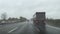 Car overtaking and passing a large truck on a highway in rain weather.