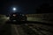 a car is parked on a dirt road at night