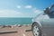 Car parked on parking lot at seashore near the beach with seascape and blue sky in the background.