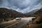 Car parked on scenic mountain wet road curve at rainy cloudy day. Road trip concept