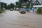 Car passes through a flooded street, damage after a storm. Floods and natural disasters.