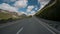 Car quickly rides along asphalt road in countryside in summer day outdoor along mountains.