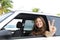 Car rental: happy woman in her car near the beach