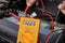 Car repair shop. Battery voltage measurement with a meter