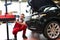 Car repair shop - worker checks and adjusts the headlights of a