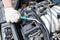 A car repairman unscrews parts with a wrench with a green handle in the engine compartment suh as spark plugs and ignition coils