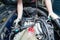 A car repairman unscrews parts with a wrench with a green handle in the engine compartment suh as spark plugs and ignition coils