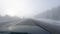 The car rides on the road among the trees covered with snow, thick fog