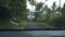 Car rides somewhere in narrow concrete road in rural tropical area on summer day