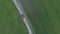 Car riding off road in fields of wheat, top aerial view. Car rides through agricultural fields in the countryside, drone shot