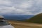 Car roof rack with light plastic cargo box for traveling. Mountain with dark clouds on background