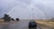 Car at roundabout with rainbow rising