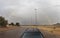 Car at roundabout with rainbow rising