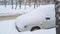 A car`s front part buried in snow after a blizzard.