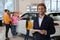 Car salesman with tablet and blurred family near auto