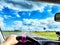 Car salon, steering wheel, hand of woman and view on nature landscape. View from seat of driver on Road, forest, blue