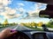 Car salon, steering wheel, hand of woman and view on nature landscape. View from seat of driver on Road, forest, blue