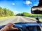 Car salon, steering wheel, hand of woman and view on nature landscape. View from seat of driver on Road, forest, blue