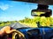 Car salon, steering wheel, hand of woman and view on nature landscape. View from seat of driver on Road, forest, blue