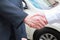 Car seller and businessman handshake at car dealership.