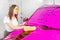 Car service detailing wash, girl worker with yellow sponge clean surface of pink foam