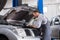 Car service worker carries out diagnostics and car repairs in the room