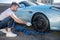 Car service worker pumping up automobile wheel