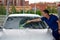 car service worker, washes the glass with a brush with foam