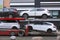 Car shipping auto transport vehicle with cars loaded in front of office buildings
