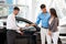 Car Showroom. Young Couple Buying a New Car at Dealership.