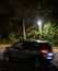 Car silhouette light trails driving fast near green park