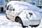 car in the snow against the background of the house on a sunny day, a large snow drift